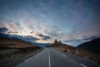 Empty road along landscape against sky