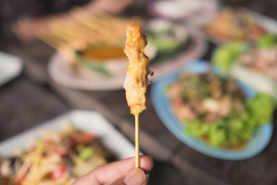 Close-up of hand holding pork satay