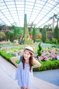 Portrait of smiling woman standing against eiffel tower replica and plants