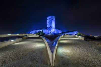 Low angle view of illuminated lighting equipment against blue sky