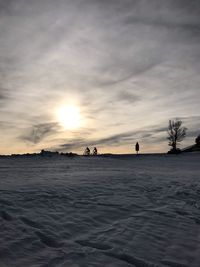 Silhouette people on land against sky during sunset