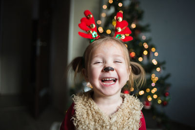 Portrait of young woman standing against christmas tree