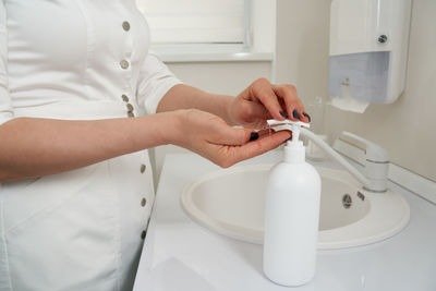 Midsection of woman holding camera at home