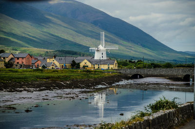 Scenic view of river by buildings against sky