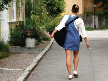 Rear view of woman walking on footpath in city