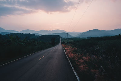 Road by mountains against sky during sunset