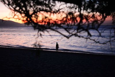 Silhouette of person on sea against sky during sunset