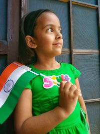 Portrait of a girl looking away while standing against window