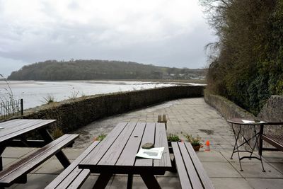 Empty swimming pool by lake against sky