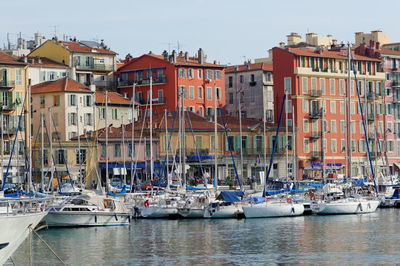 Sailboats moored on sea against buildings in city