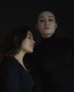 Portrait of young couple looking away against black background