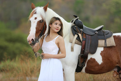 Young woman standing by horse