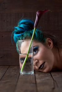 A young girl looking through a glass full of water with a flower inside