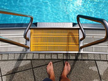 Low section of man standing by swimming pool