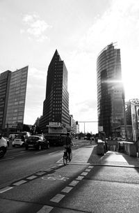 City street by modern buildings against sky