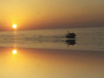 Silhouette of boat in sea during sunset