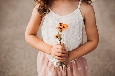 Young girl holding yellow flowers outside on a warm day