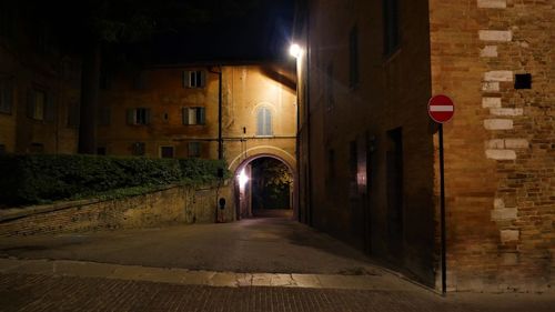 Empty road along buildings at night