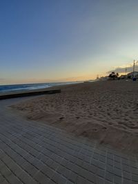 Scenic view of beach against clear sky at sunset