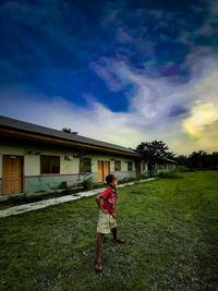 Girl standing by building against sky