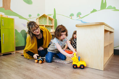 Teacher watches student as they play together with toy cars