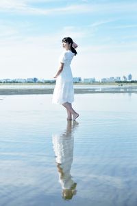 Full length of woman standing on shore against sky