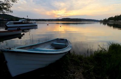 Sailboats moored on lake against sky during sunset