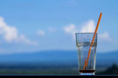 Close-up of drinking glass on table against blue sky