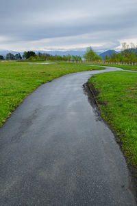 Road amidst field against sky