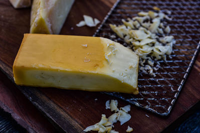 Smoked cheese and metal grater on wood cutting board