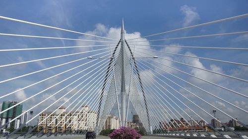 Low angle view of suspension bridge against cloudy sky