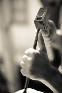 Close-up of cropped hand holding object over white background