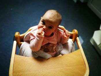 Portrait of baby girl relaxing in high chair at home