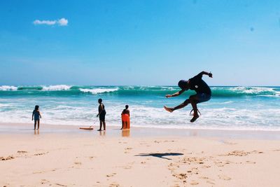 People at beach against sky during summer