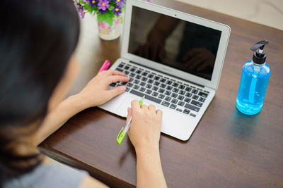 Midsection of woman using mobile phone while sitting on table