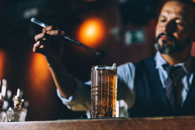 Bartender preparing cocktail at counter in bar