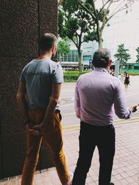 Rear view of men walking on street in city