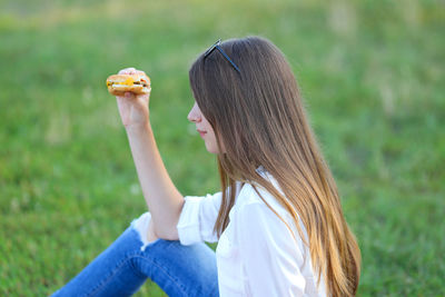 Side view of woman holding leaf on field