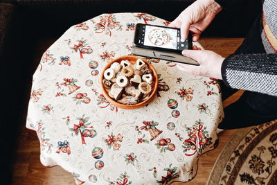 High angle view of woman holding taking photo of food on table