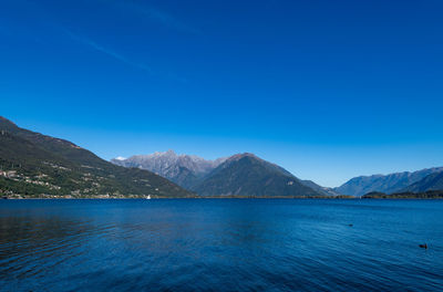 Scenic view of sea and mountains against clear blue sky