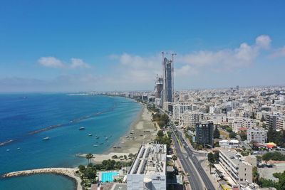 High angle view of city by sea against blue sky