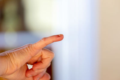 Cropped hand of man gesturing against window