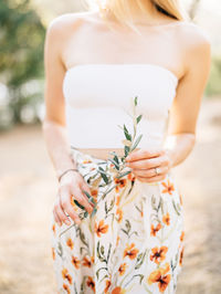 Midsection of woman holding white flower