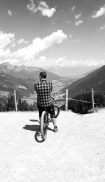 Rear view of man riding bicycle on mountain