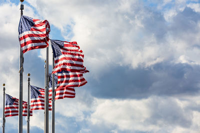 Low angle view of red flags against cloudy sky