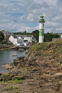 Lighthouse amidst buildings against sky