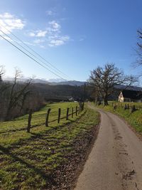 Road amidst field against sky