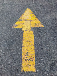 Close-up of yellow arrow symbol on road