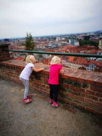 Rear view of girl with umbrella against built structure