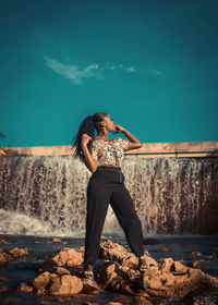 Portrait of young woman standing on rock against dam